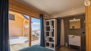 Un dormitorio con cama, tocador y vista a un paisaje nevado.