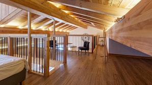 Un dormitorio estilo loft con techo inclinado, una cama, un escritorio y una silla.