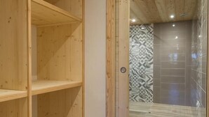 Un interior de madera con una puerta corredera de vidrio que da a un baño con baldosas estampadas.