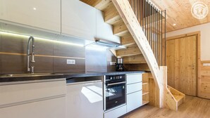 Una cocina moderna con electrodomésticos de acero inoxidable, una escalera de madera y una puerta de madera.