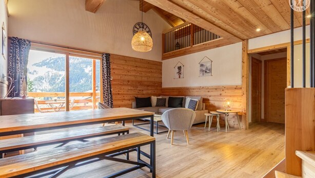 Un interior acogedor de madera con comedor, un sofá y una pequeña mesa.