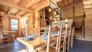 Un interior de madera con una mesa de comedor lista para seis personas, rodeada de sillas de madera.