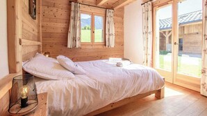 Habitación de cabaña de madera con cama, cortinas y ventana con vista a la montaña.