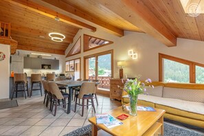 A modern interior with a dining area, kitchen, and a sofa with a view.