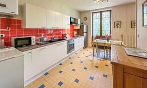 A kitchen with white cabinets, a microwave, a stove, and a dining area with a table and chairs.