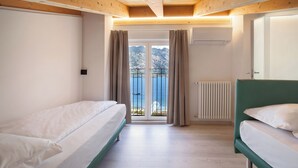 A bedroom with two beds, a view of the sea, and a wooden ceiling. - Frantoio a Monte-Apartment near the lake (Malcesine)
