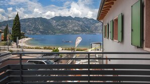A balcony with a view of a lake, mountains, and a beach. - Frantoio a Monte-Apartment near the lake (Malcesine)