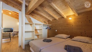 A cozy wooden cabin with two beds, a TV, and a seating area with a TV and chair. - LE Davo - Hauteluce - Gîte (HAUTELUCE)