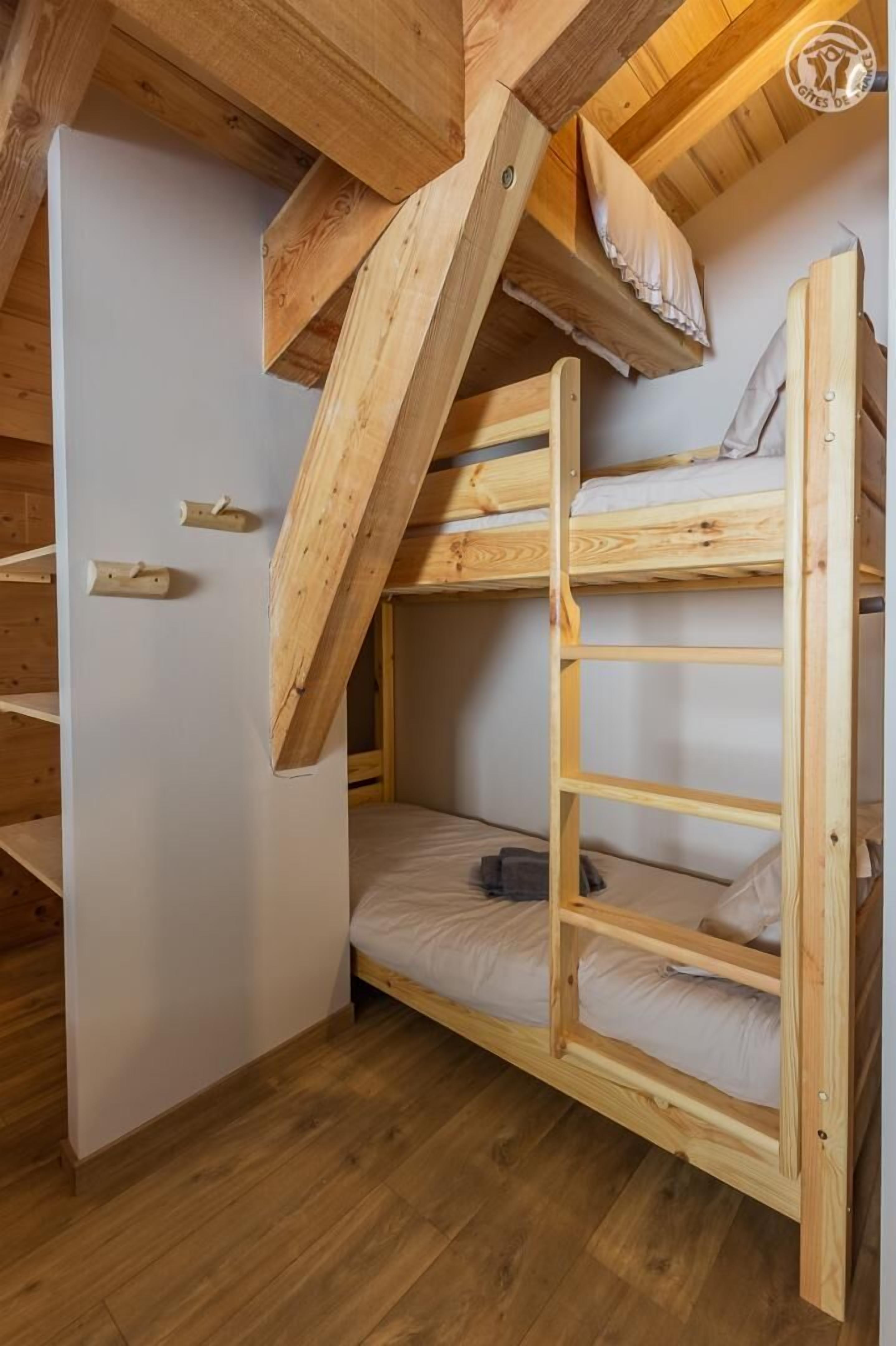 A bunk bed with a wooden frame and a slanted ceiling.