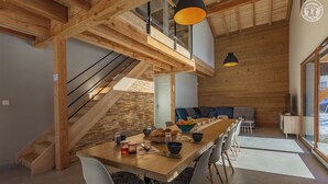 A modern interior with a wooden dining table, chairs, and a staircase. - LE Davo - Hauteluce - Gîte (HAUTELUCE)