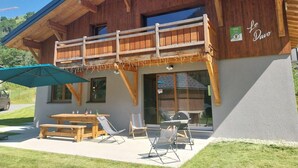 A wooden building with a balcony, outdoor seating, and a sign reading "Le Davo". - LE Davo - Hauteluce - Gîte (HAUTELUCE)