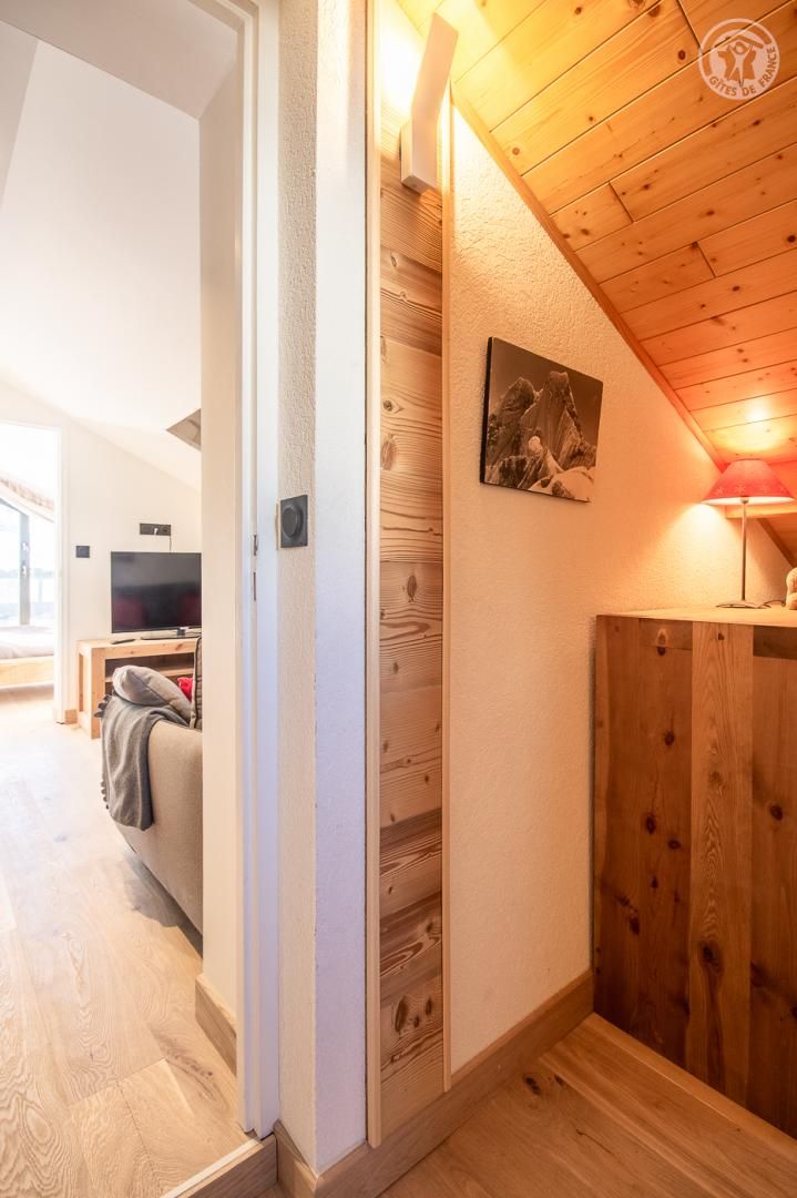 Una habitación acogedora con techo de madera, televisor y sofá.