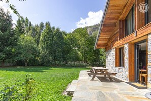 A wooden cabin with stone walls, a stone patio, and a view of a forested area. - L'alpette - Valloire (VALLOIRE)