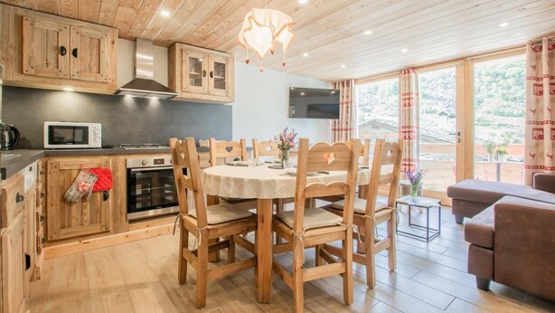 A wooden interior with a kitchen, dining area, and a sofa. - LES Lauzes 1 - Bonneval SUR ARC (BONNEVAL SUR ARC)