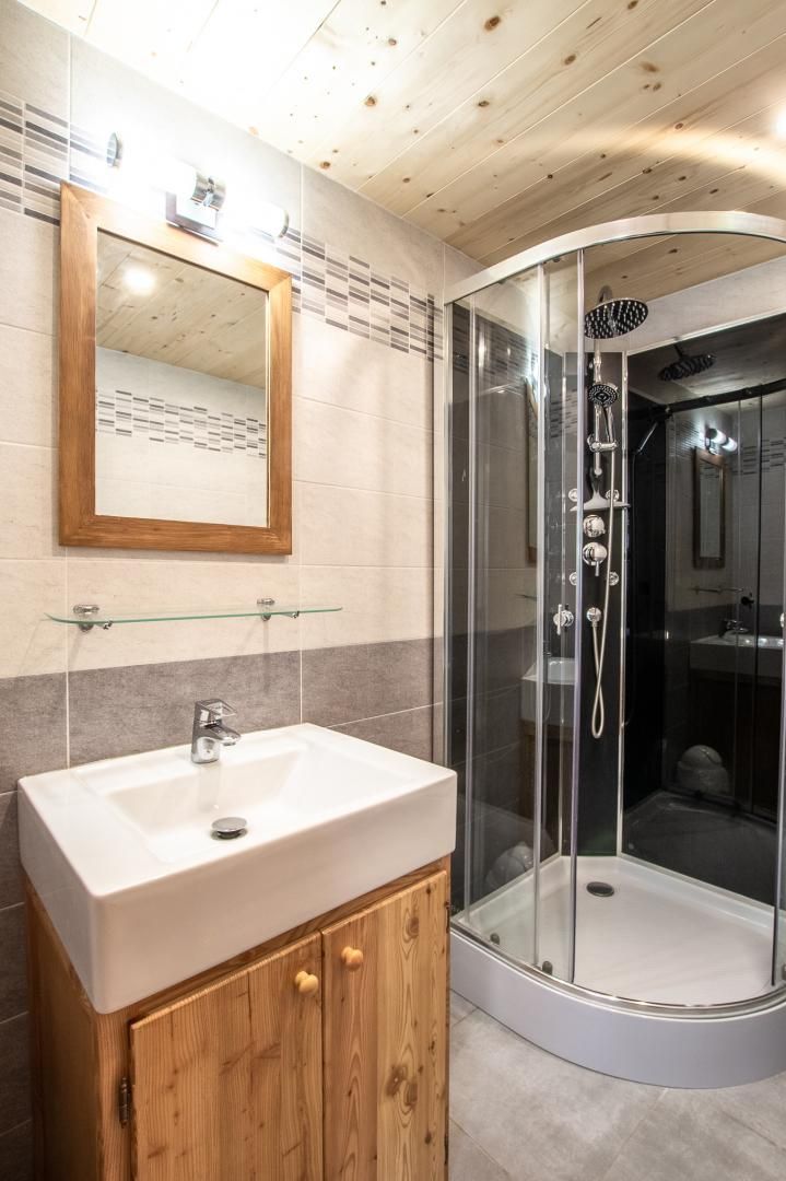 Une salle de bain moderne avec une douche à parois de verre, un meuble-lavabo en bois et un miroir.