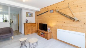 A modern living room with a wooden wall, a TV, a cabinet, and two small tables. - LE Barillon - Avrieux (AVRIEUX)