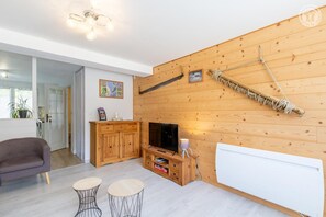 A modern living room with a wooden wall, a TV, a cabinet, and two small tables. - LE Barillon - Avrieux (AVRIEUX)