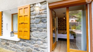 A stone building with a bedroom featuring a bed, a nightstand, and a hanging light fixture. - LE Barillon - Avrieux (AVRIEUX)
