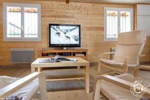Relax in a comfortable seating area with a sofa and armchairs, featuring a flat-screen television and a small wooden table.