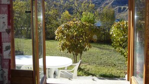 A room with a large window offering a view of snow-capped mountains and a grassy landscape with trees.