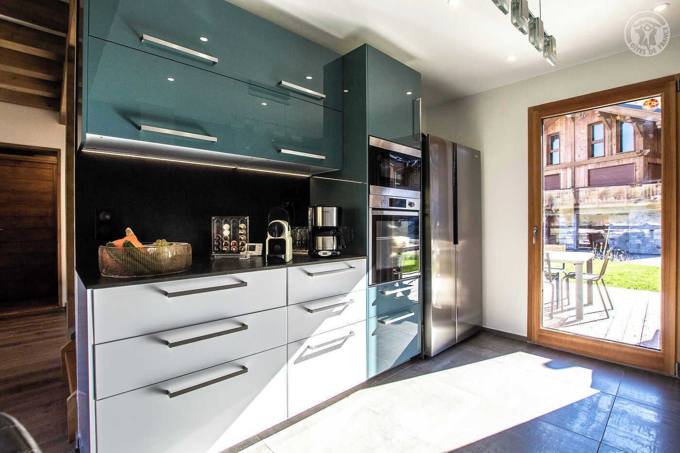 Una cocina moderna con armarios oscuros, electrodomésticos de acero inoxidable y una puerta corrediza de vidrio que da a un patio exterior.