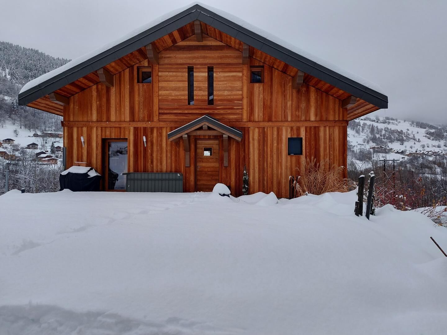 A wooden cabin with a gabled roof, a front door, and two windows on the upper floor.
