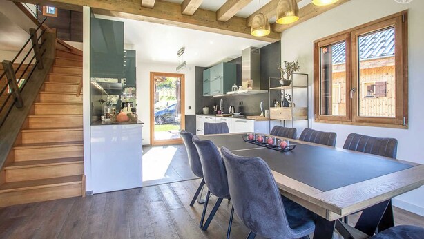 Una cucina moderna con zona pranzo, travi in legno e una scala.