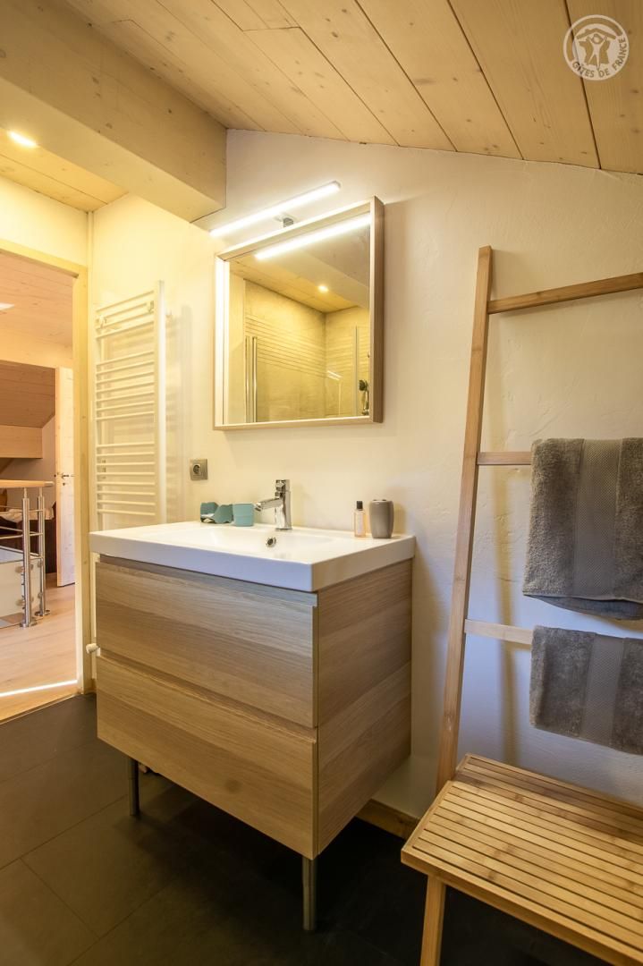 A modern bathroom with a wooden vanity, a mirror, and a towel rack.