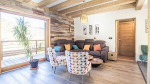 Un accogliente soggiorno con un divano, poltrone a fantasia e soffitto in legno.