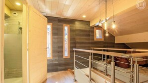 Un interno moderno con una scala in legno, una zona doccia e vista attraverso una finestra.