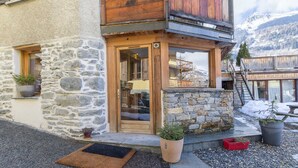A stone building with a wooden balcony and a door. - Maison Adele - Ste-foy-tarentaise (SAINTE FOY TARENTAISE)