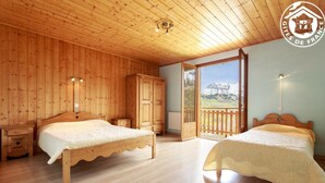 A wooden-paneled bedroom with two beds, a wardrobe, and a balcony with a mountain view. - LE Petit Bonheur - St-jean-d'arves (SAINT JEAN D'ARVES)