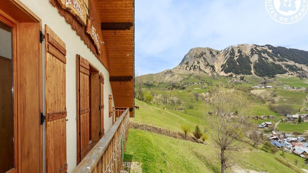 A wooden building with a balcony and a mountainous landscape in the background. - LE Petit Bonheur - St-jean-d'arves (SAINT JEAN D'ARVES)