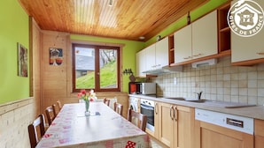 A dining area with a table set for four, wooden cabinets, a microwave, and a dishwasher. - LE Petit Bonheur - St-jean-d'arves (SAINT JEAN D'ARVES)