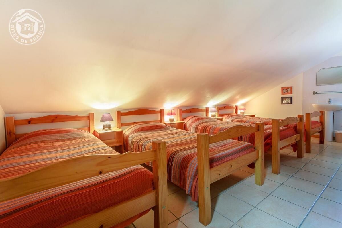 A dormitory room with multiple wooden beds, each with a striped blanket.