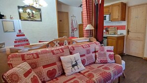 A cozy living room with a sofa adorned with festive patterns and a 'Merry Christmas' sign.