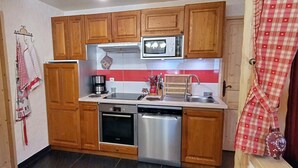 A compact kitchen with wooden cabinets, a microwave, a coffee maker, and a dishwasher.