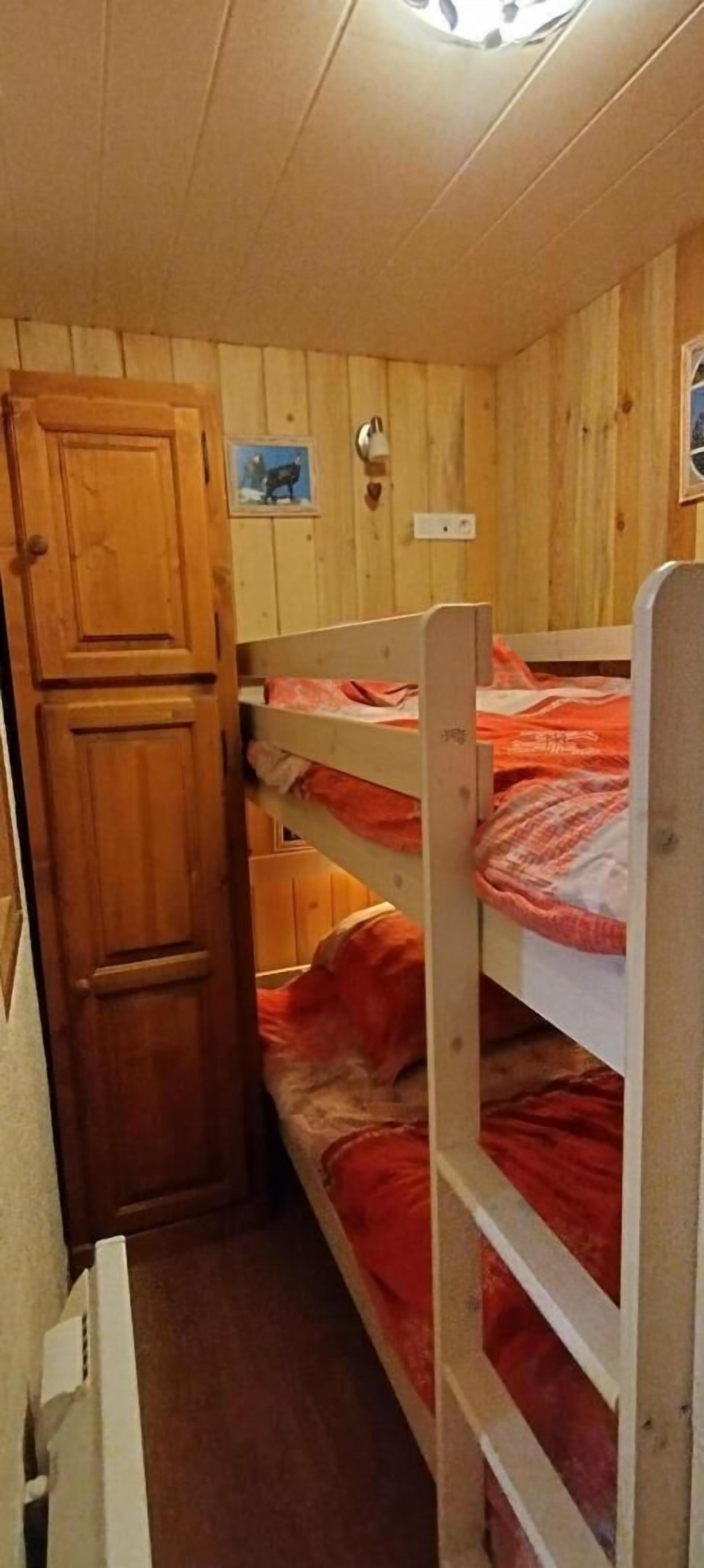 Habitación con literas, paredes de madera y una puerta.