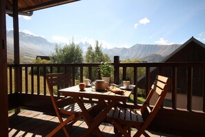 Un pontile in legno con un tavolo apparecchiato per la colazione, affacciato su un paesaggio montuoso.