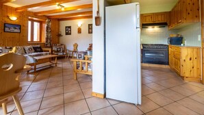 A cozy cabin-style room with a wooden interior, a dining area with a bench, and a kitchen with wooden cabinets and a stove.
