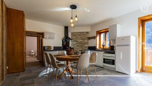 Une cuisine moderne avec un coin repas, dotée d’un pare-feu en pierre, d’un four encastré et d’une grande fenêtre offrant une vue dégagée.