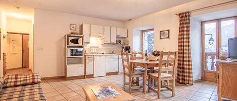 Un espacio habitable compacto con kitchenette, comedor y sofá.