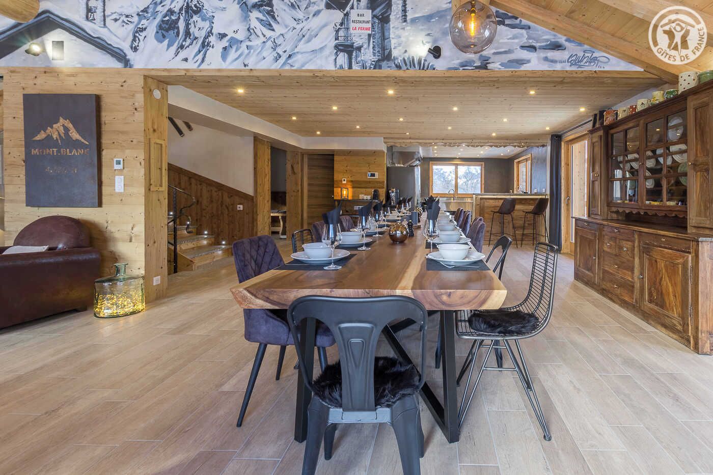 Comedor con una larga mesa de madera dispuesta para una comida, rodeado de sillas.