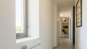 A hallway with a radiator, a window, and a hanging light fixture. - Gite DU Miron - St-paul-sur-yenne (ST-PAUL-SUR-YENNE)