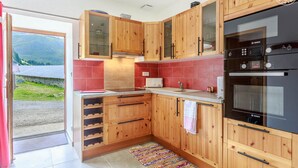 Une cuisine moderne avec des meubles en bois, un four Bosch et un pare-feu en carreaux rouges.