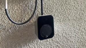 Une borne de recharge pour véhicules électriques avec un câble branché sur une prise murale.