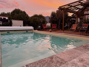 En swimmingpool med liggestole og en pergola.
