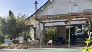 Une piscine dotée de chaises longues et d’une structure en forme de pergola.