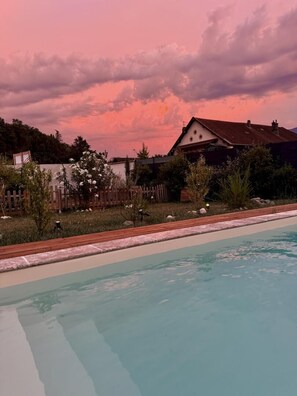 Une piscine avec une terrasse en bois et une clôture en bois en arrière-plan.
