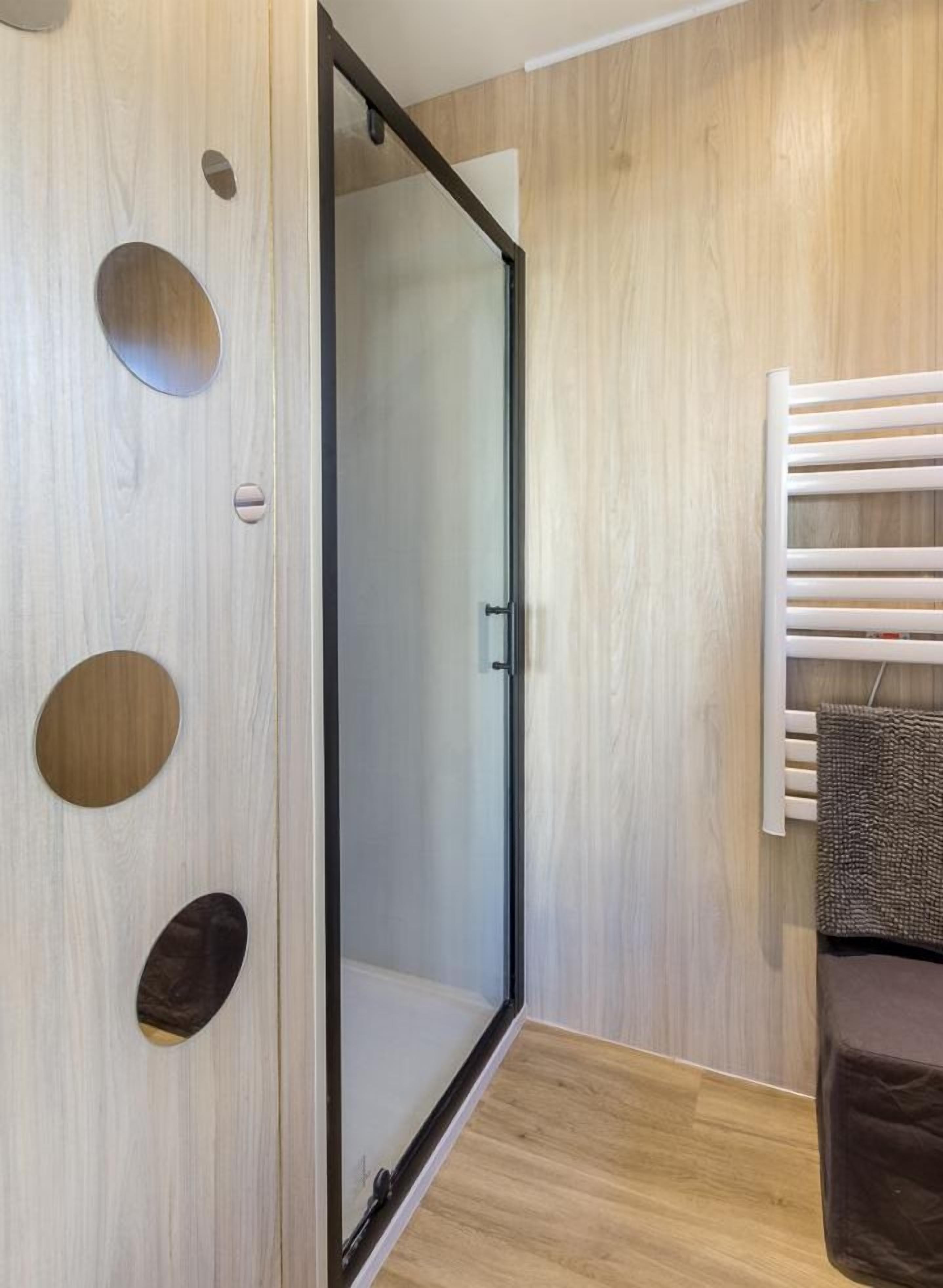 Un baño moderno con pared de madera, cabina de ducha de vidrio y un perchero para toallas.